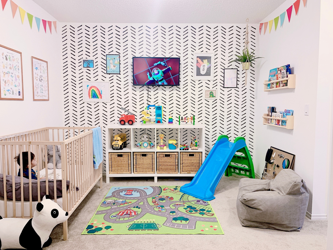 a baby's room with a chevron patterned wall, crib and slide in a kids playroom bright and colorful play area for children 