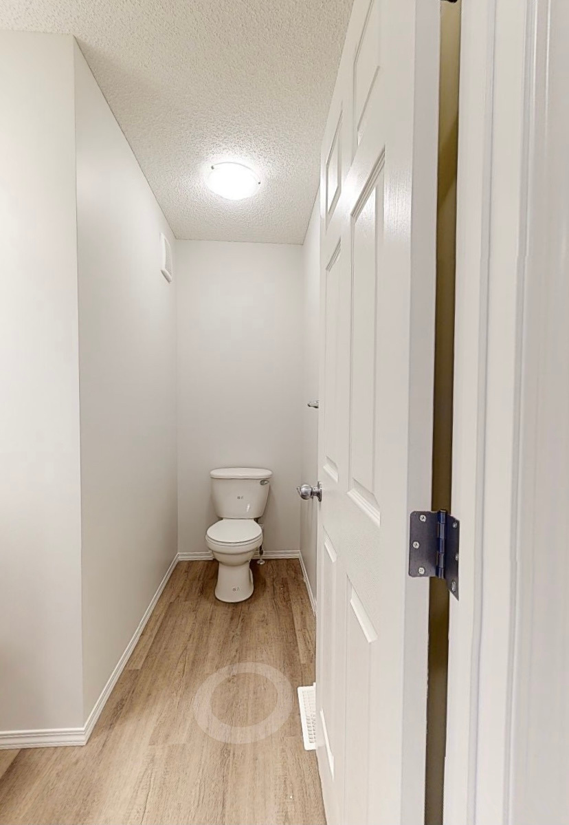 a small bathroom with a toilet and a door by Sterling Homes in Edmonton Alberta