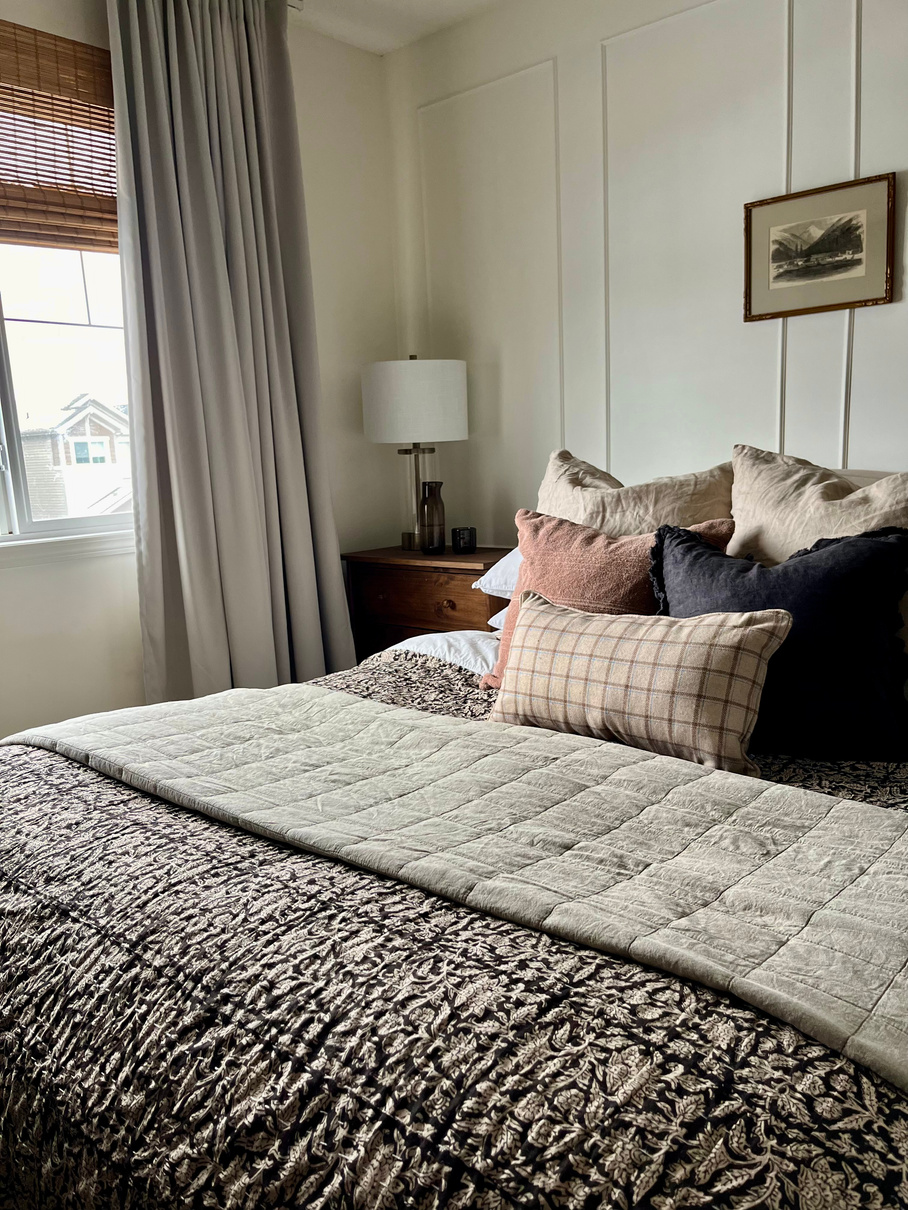 a cozy bedroom with a large bed and a window design by interior designer near me in Edmonton Alberta