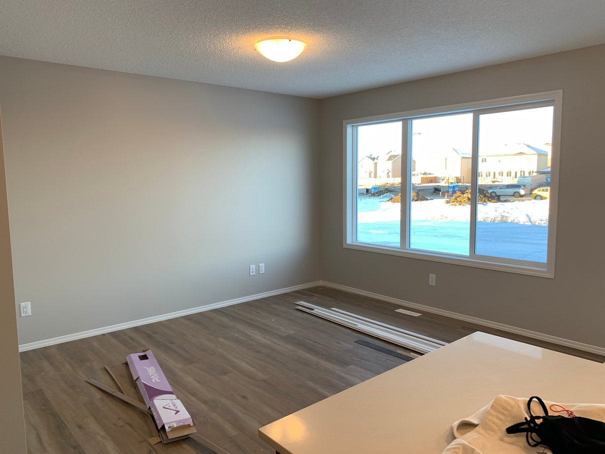 an empty room with hardwood floors and a window by Sterling home in Edmonton Alberta