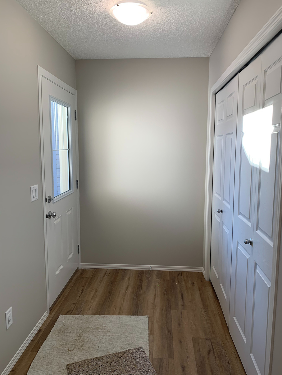 an empty room with white doors and hardwood floors by Sterling home in Edmonton Alberta